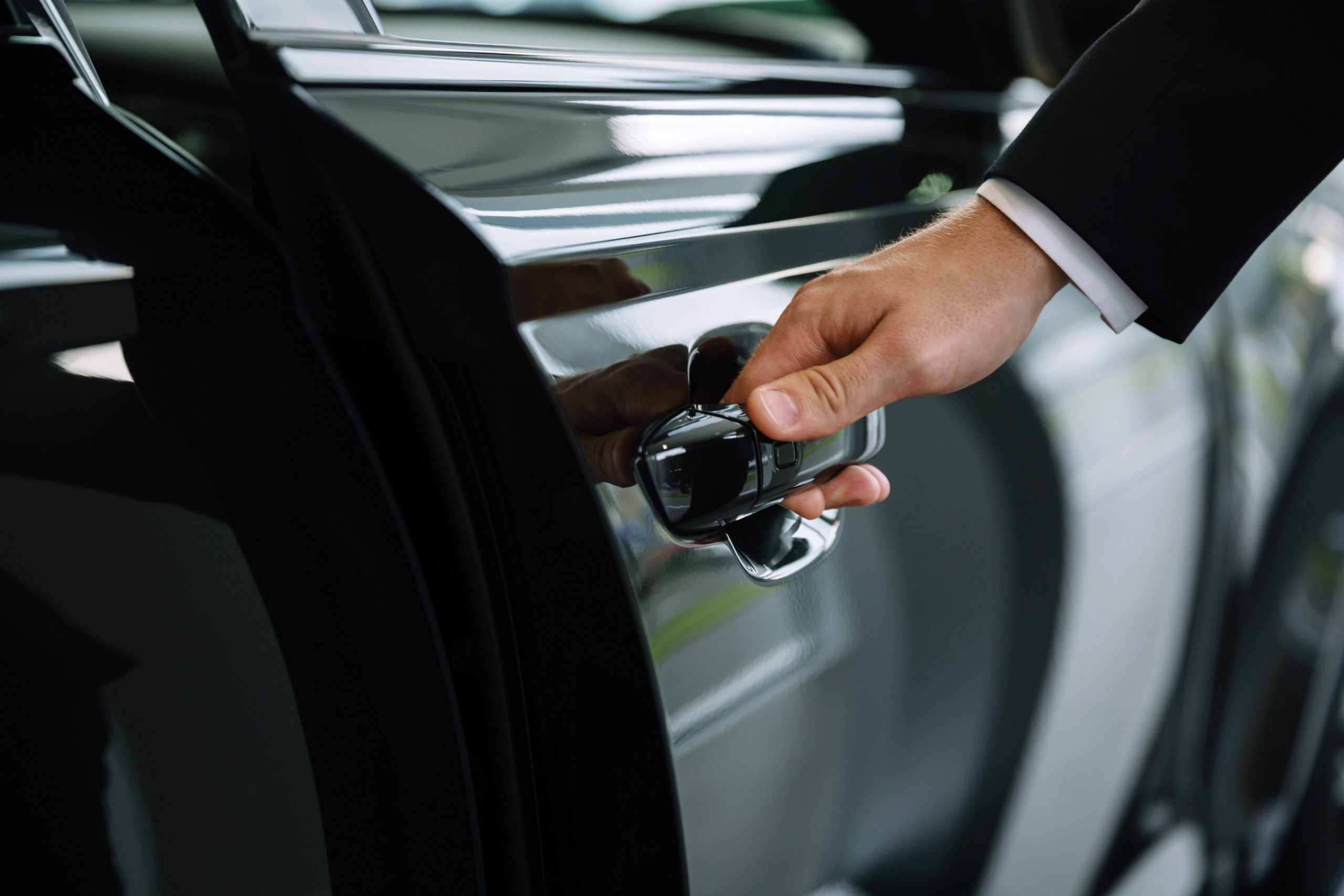 man in a black suit opening a car door