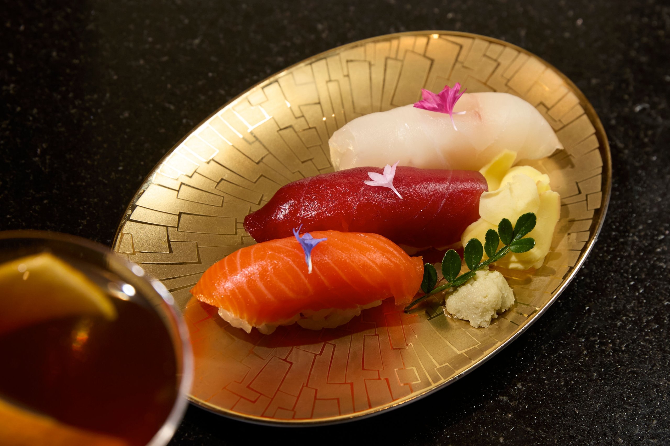 an image of three pieces of sushi on a gold plate